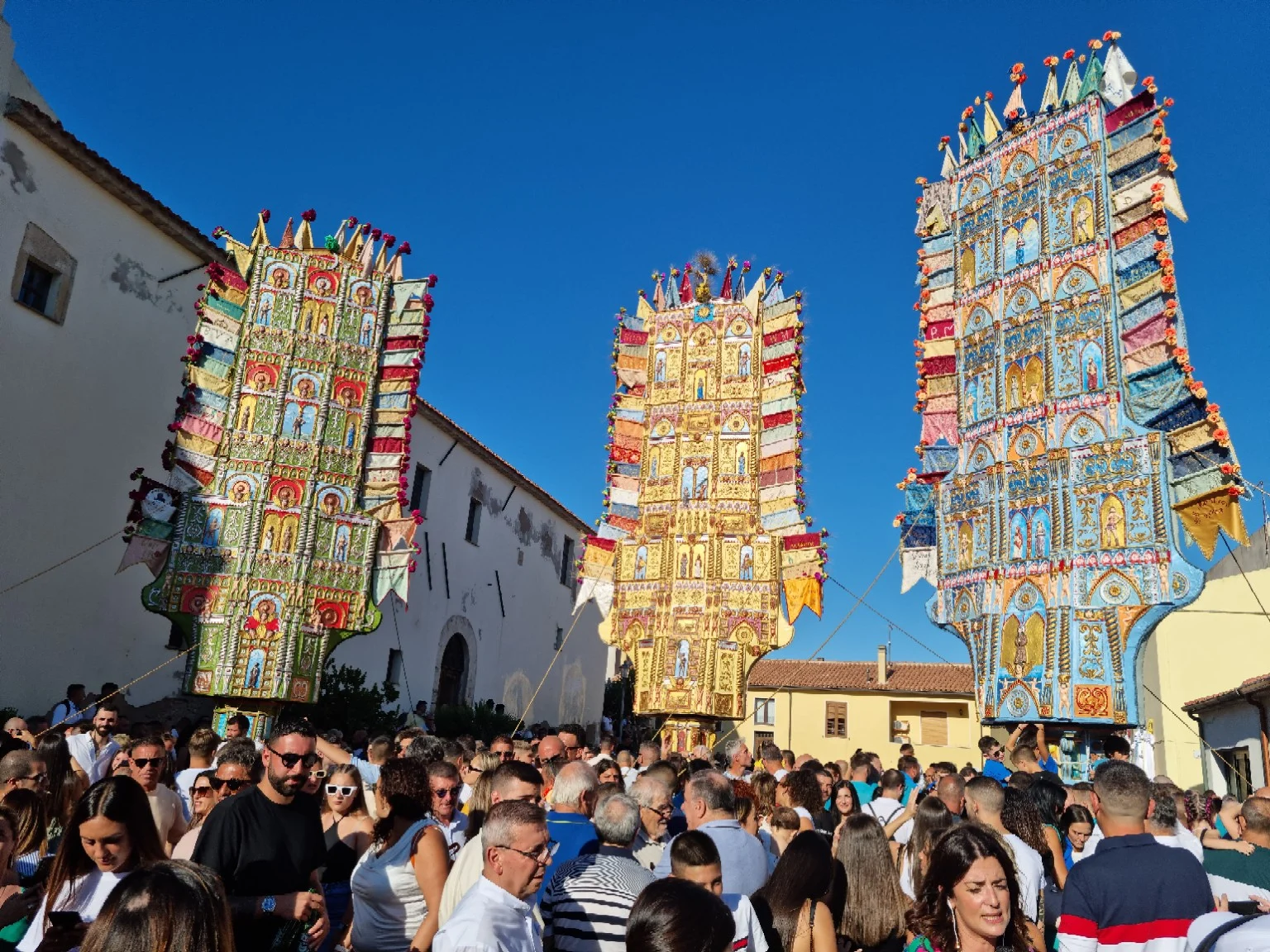 Crowds gathering beneath the colourful Candelieri in Nulvi