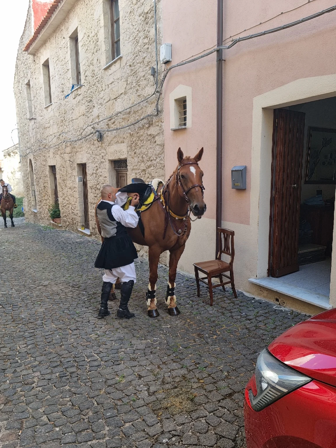 A rider in traditional dress preparing his horse in the village